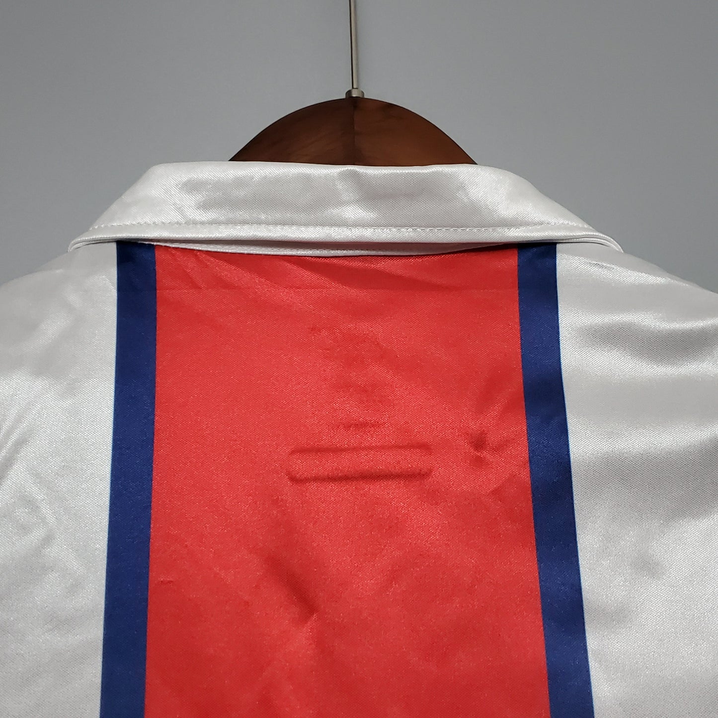 Detalle de la parte trasera de una camiseta de fútbol europea blanca con franja roja y azul
