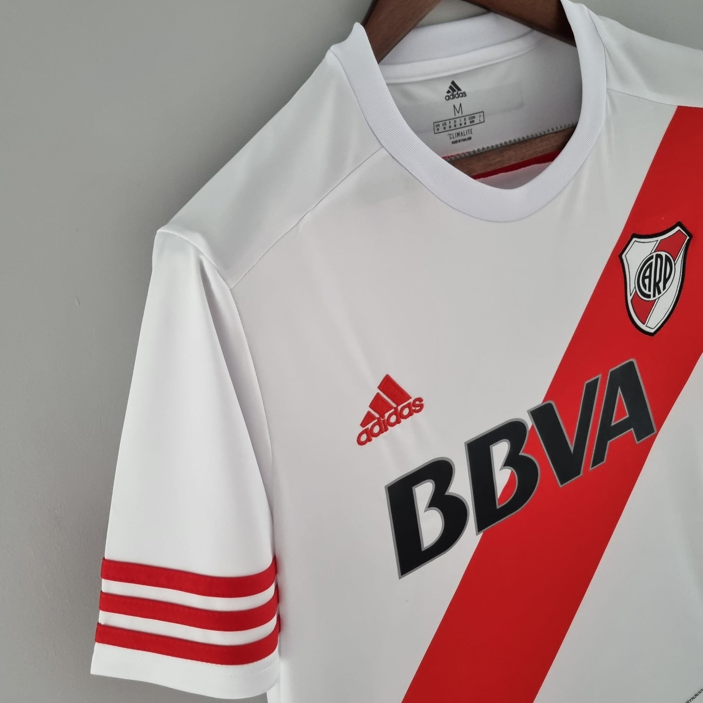 Camiseta de fútbol blanca con banda roja, logo de River Plate y Adidas, en Reino del Futbol.