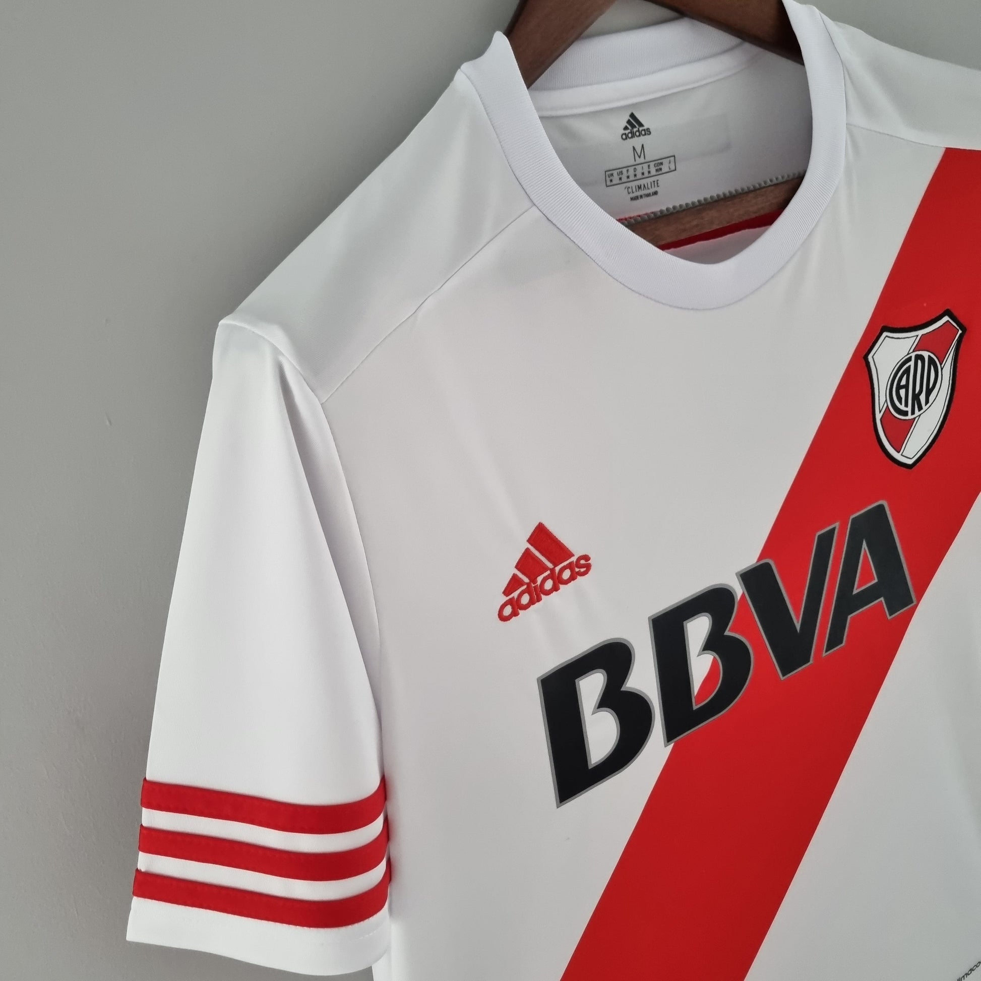 Camiseta de fútbol blanca con banda roja, logo de River Plate y Adidas, en Reino del Futbol.