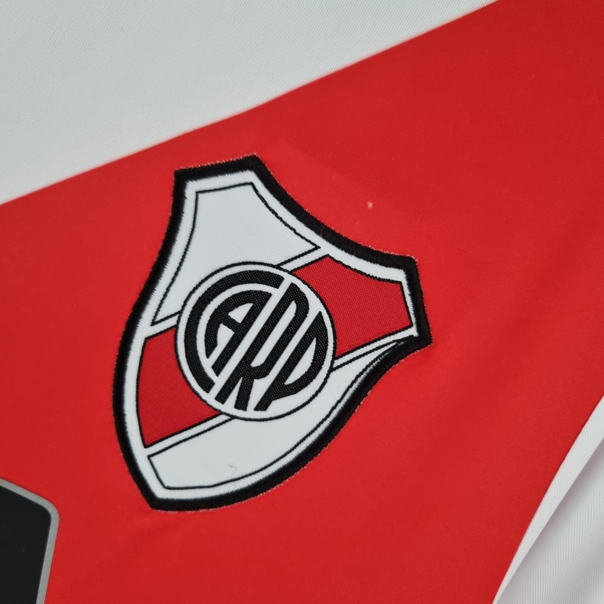 Escudo de River Plate en camiseta de fútbol blanca y roja, Reino del Futbol tienda online