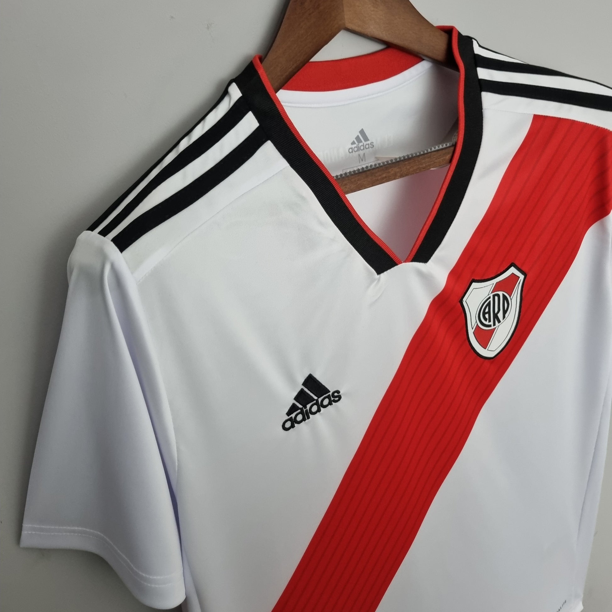 Camiseta de fútbol River Plate blanca con banda roja y logo Adidas, a la venta en Reino del Futbol