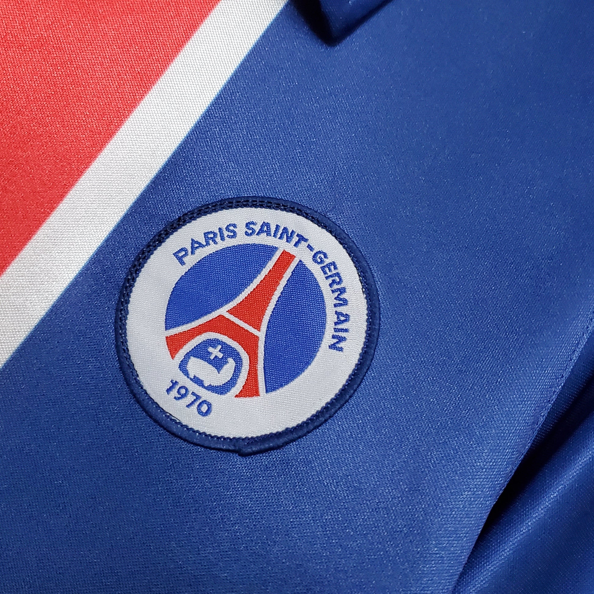 Detalle del escudo Paris Saint-Germain en camiseta azul, tienda Reino del Futbol España