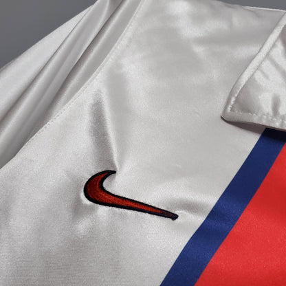 Detalle de camiseta de fútbol blanca con logo Nike, franja azul y roja, Reino del Futbol