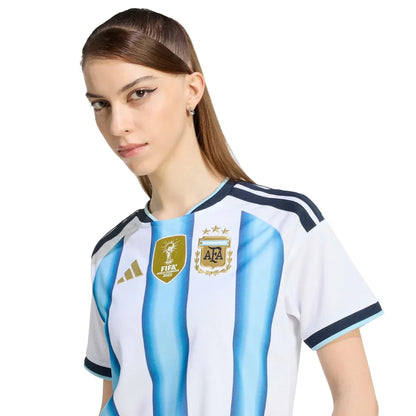 Mujer con camiseta Argentina 2026, escudo AFA y logo FIFA, Reino del Futbol
