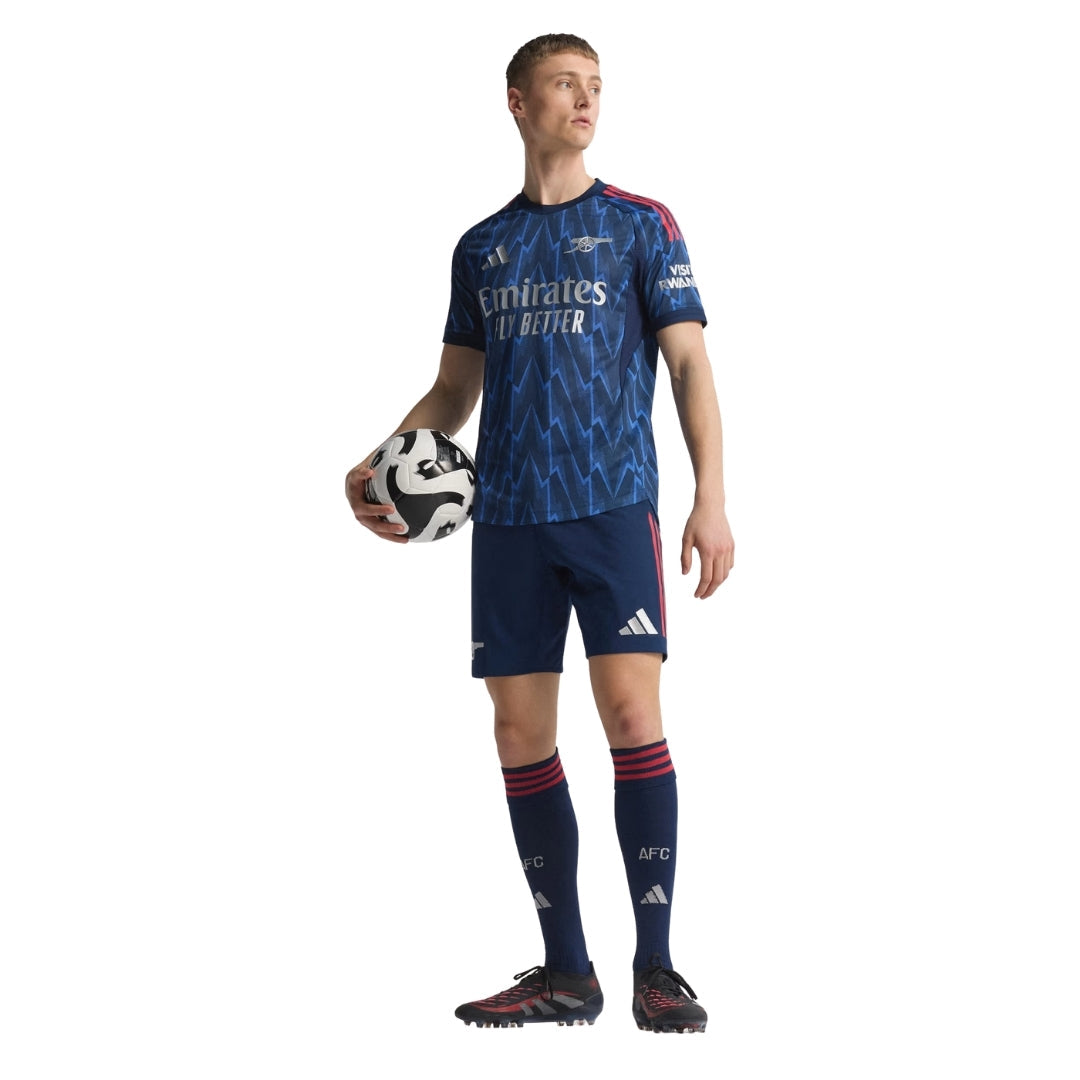 Jugador con uniforme azul Arsenal 2025-2026, balón de fútbol, fondo blanco, Reino del Futbol