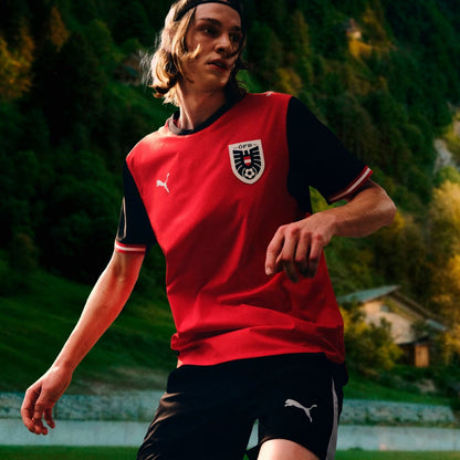 Jugador con camiseta de fútbol Austria Puma 2026 en campo verde, Reino del Futbol