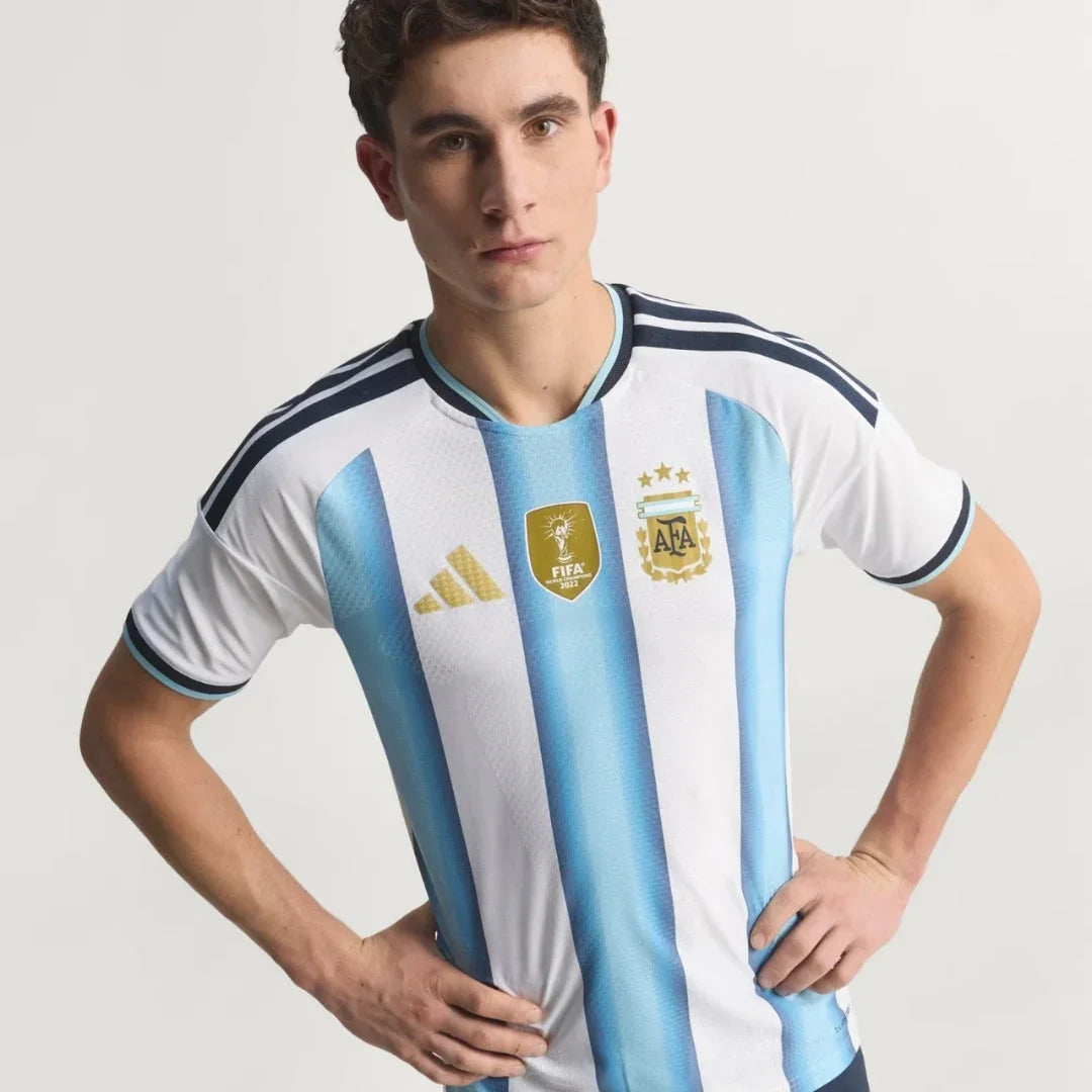 Camiseta local Argentina 2026 con escudo AFA y logo FIFA, modelo posando, Reino del Futbol