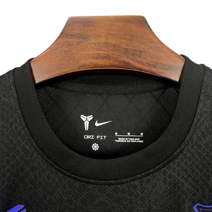 Camiseta deportiva negra Nike Dri-Fit en percha de madera, detalles del logo y tejido.