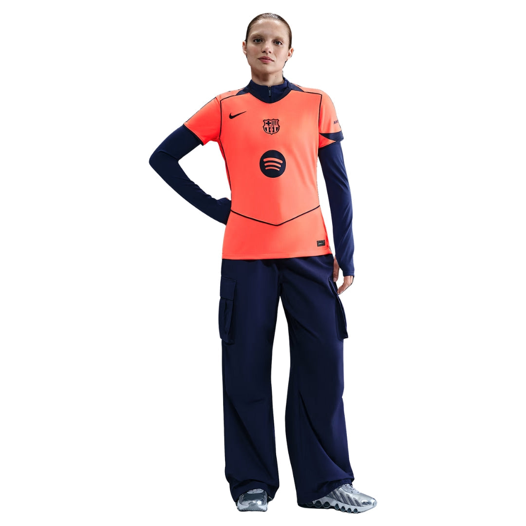 Mujer con camiseta FC Barcelona 2025 naranja y pantalón azul, moda fútbol Reino del Futbol