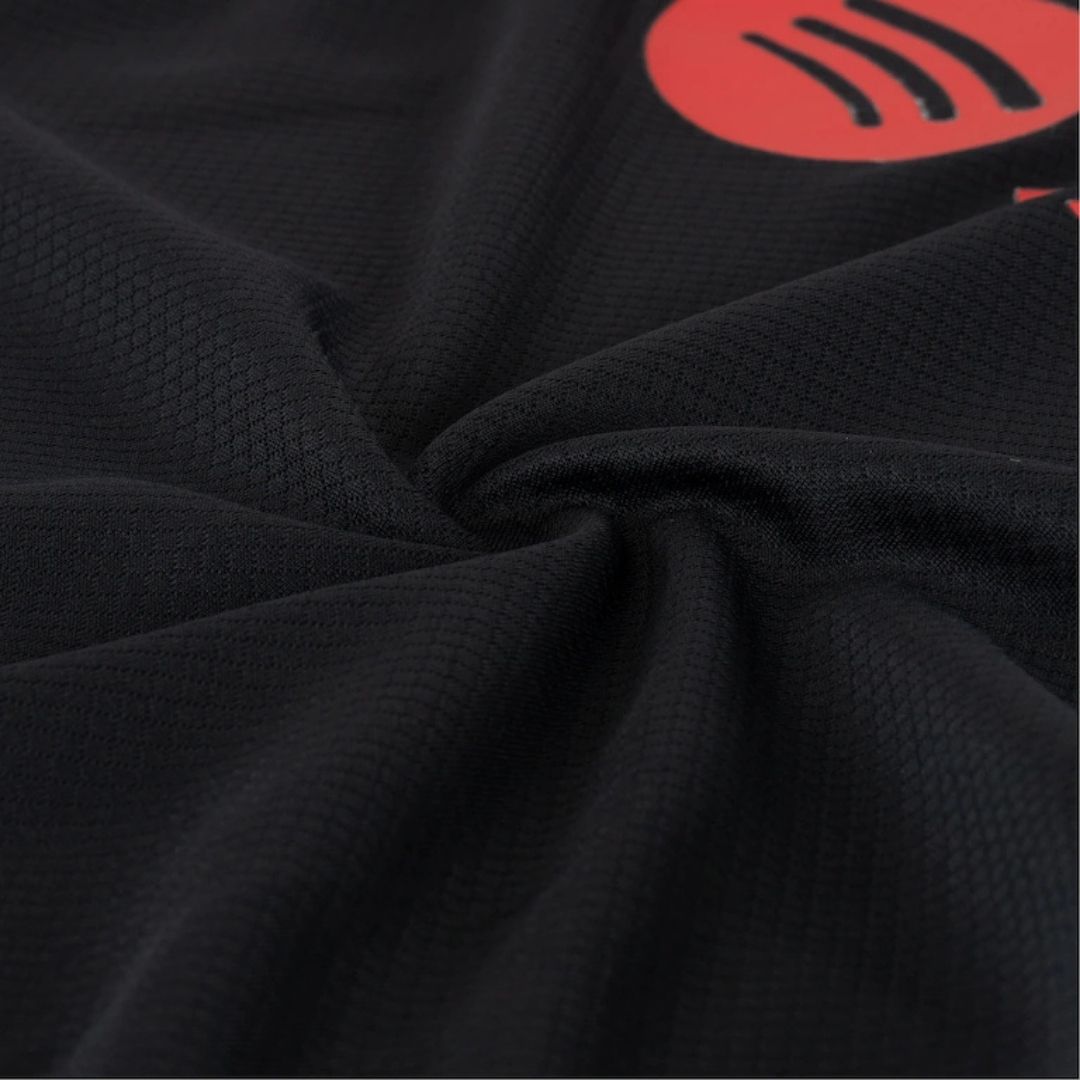 Detalle de tela de camiseta de fútbol negra con textura y logo rojo, Reino del Futbol