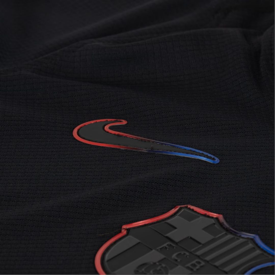 Detalle de camiseta negra FC Barcelona Nike, escudo y logo en azul y rojo, Reino del Futbol