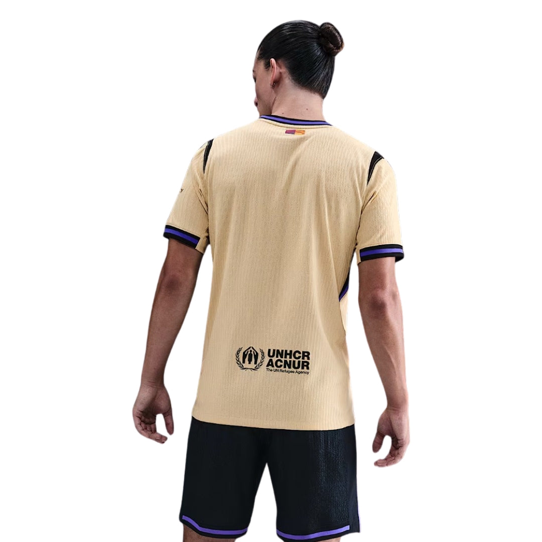 Jugador con camiseta Barcelona 2023-2024 visitante dorada, logo UNHCR ACNUR, Reino del Futbol