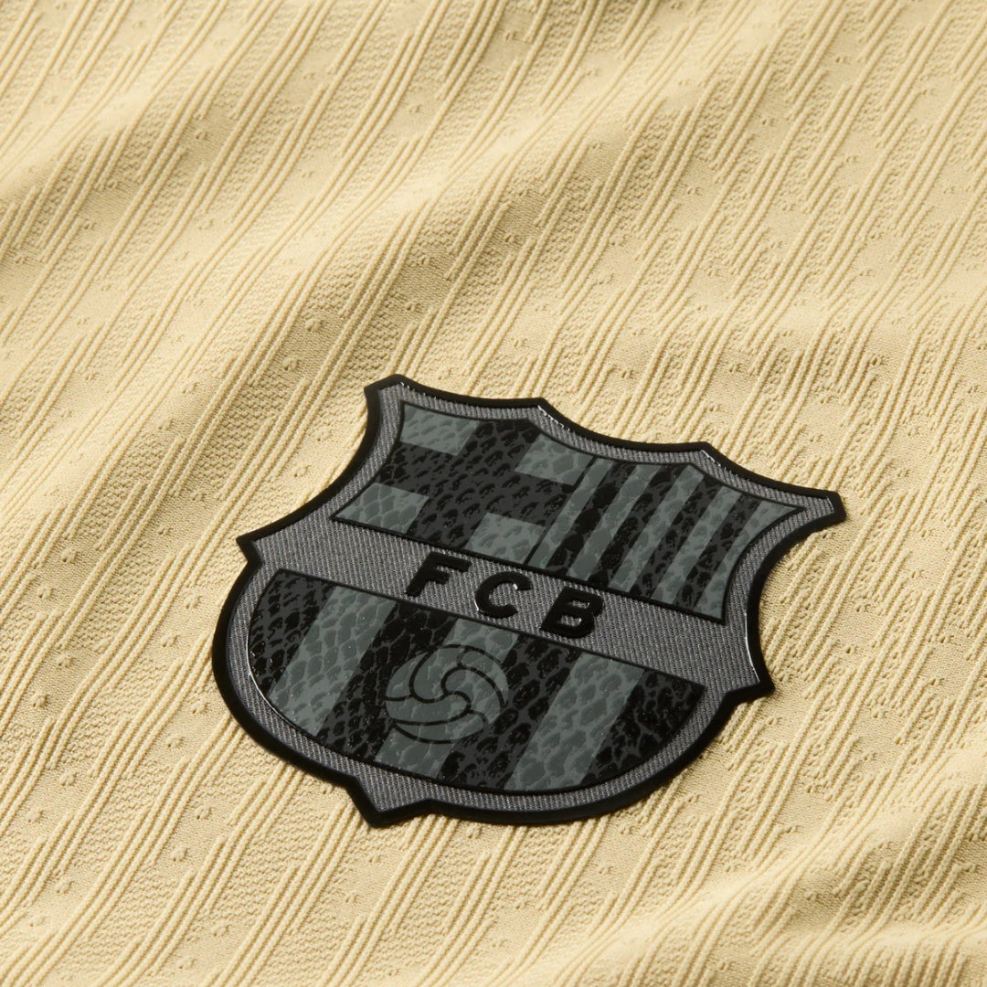 Detalle del escudo FC Barcelona en la camiseta oro de visitante, textura tejida, Reino del Futbol