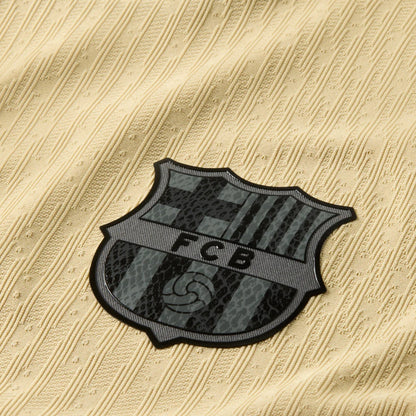 Detalle del escudo FC Barcelona en la camiseta oro de visitante, textura tejida, Reino del Futbol