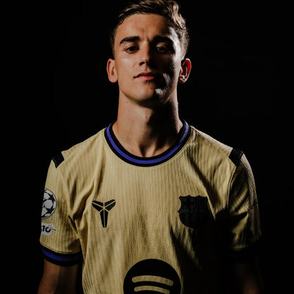 Jugador con la camiseta Barcelona 2025-26 visitante dorada, escudo y logos visibles