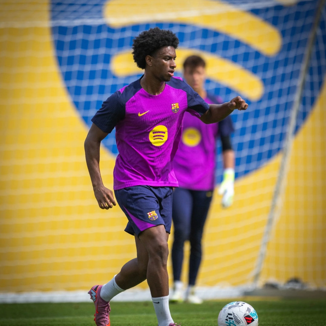 Jugador del Barcelona entrenando en cancha de fútbol, uniforme morado, Reino del Futbol
