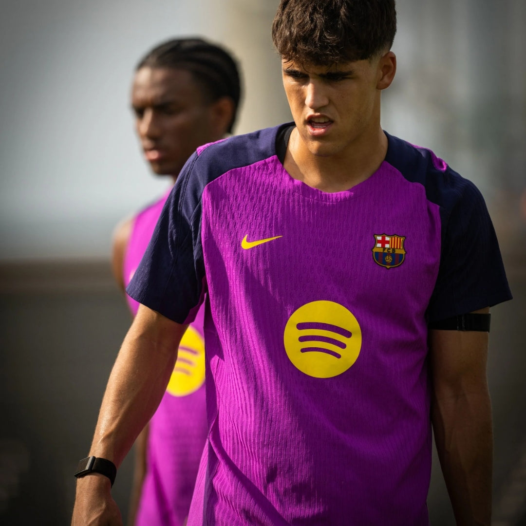 Jugadores del FC Barcelona entrenando con camiseta morada y logo amarillo al aire libre