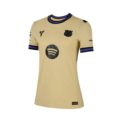 Camiseta Barcelona mujer 2025 dorada, logos Barça y Spotify, cuello y mangas azul y negro.