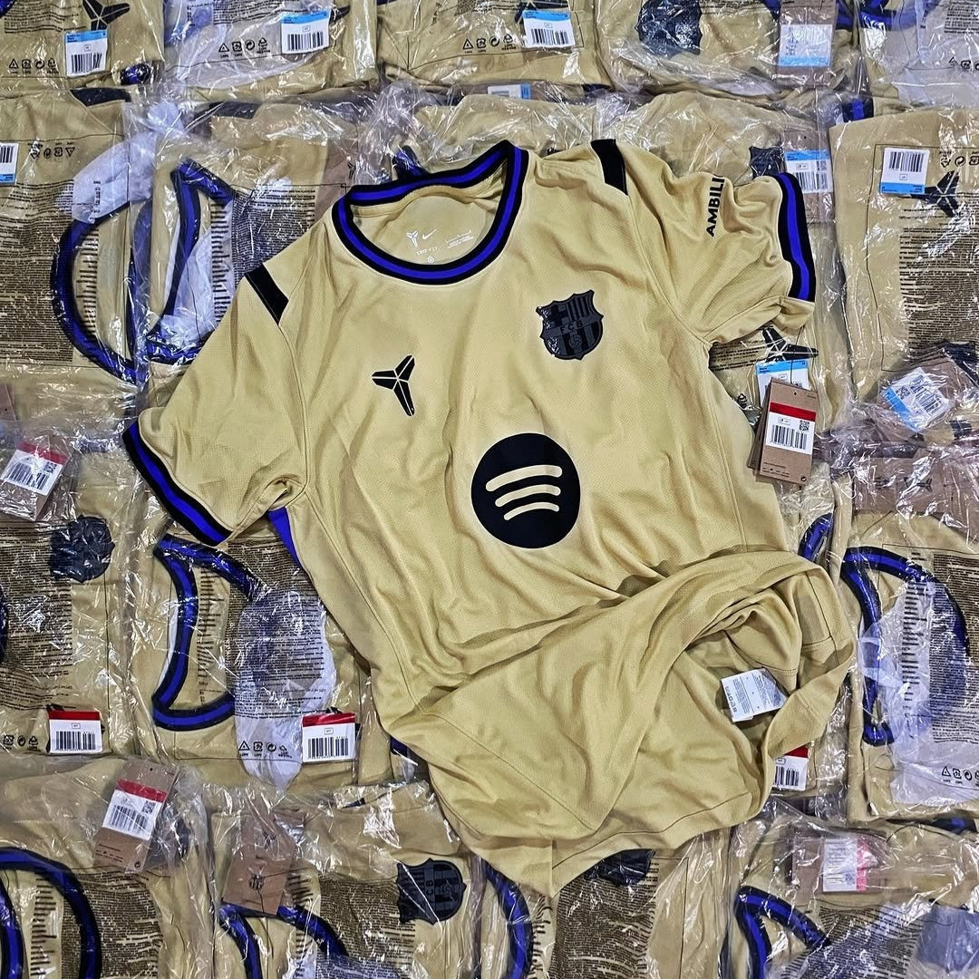 Camiseta dorada Barcelona Away 25/26 Mamba con logos negros y etiquetas, Reino del Futbol.