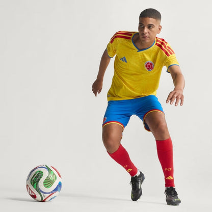 Jugador con uniforme local de Colombia 2024 controlando balón, fondo blanco, Reino del Futbol