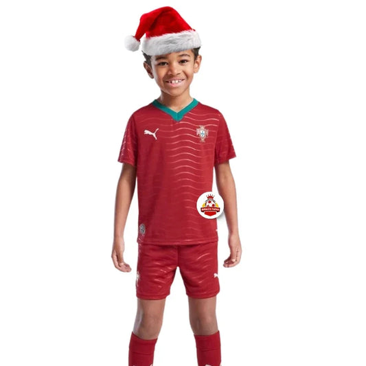Niño con gorro navideño y uniforme de fútbol rojo, logo Reino del Futbol