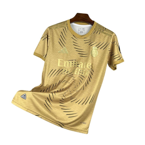 Camiseta dorada Real Madrid 2024 Adidas, logo Emirates, fondo blanco, Reino del Futbol