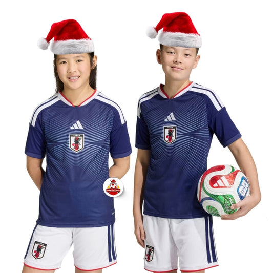 Niños con uniforme de fútbol de Japón y gorros navideños, balón, fondo blanco, Reino del Futbol