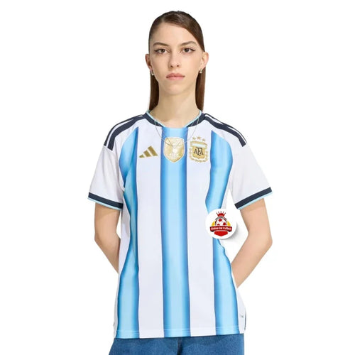 Mujer con camiseta oficial de Argentina, fondo blanco, logo Reino del Futbol visible