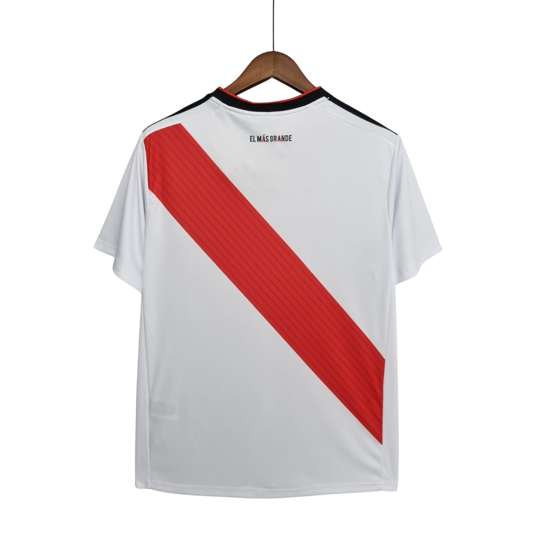Camiseta de fútbol blanca con banda roja diagonal, exhibida en percha, exclusiva Reino del Futbol.