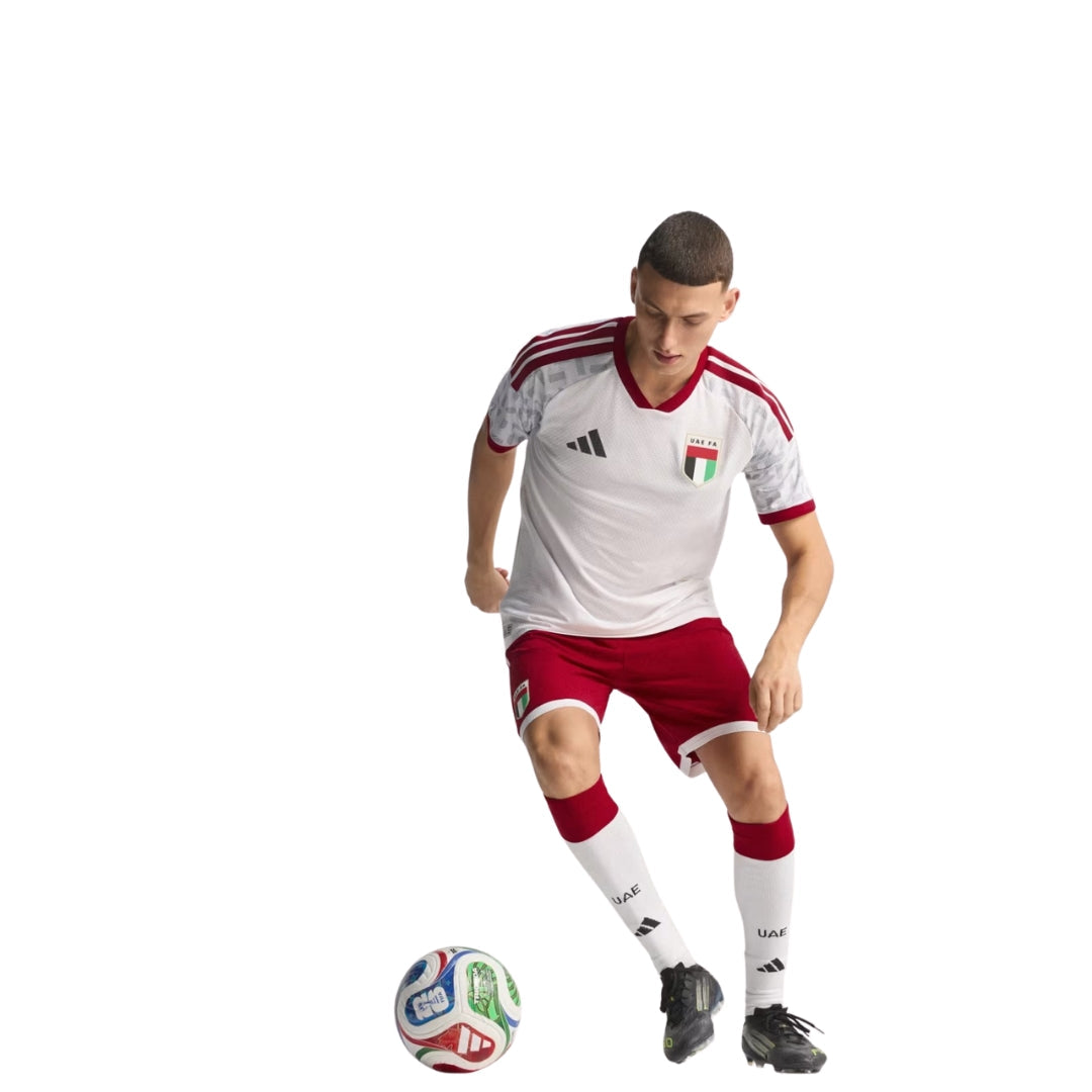 Futbolista con uniforme de Emiratos Árabes, balón oficial Copa Mundial 2026, fondo blanco