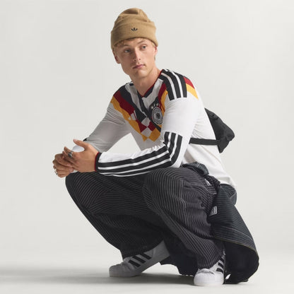 Hombre con camiseta Alemania retro, fondo blanco, moda Reino del Futbol, estilo deportivo.