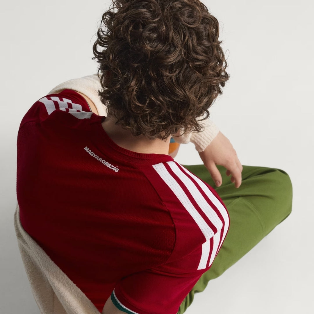 Persona con camiseta de fútbol Hungría roja, detalle de rayas blancas y texto Magyarország