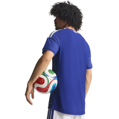 Jugador con camiseta de fútbol azul, balón en mano, fondo blanco, Reino del Futbol