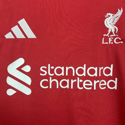 Camiseta Liverpool local 2025/26 roja con logos Adidas, Standard Chartered y escudo LFC.