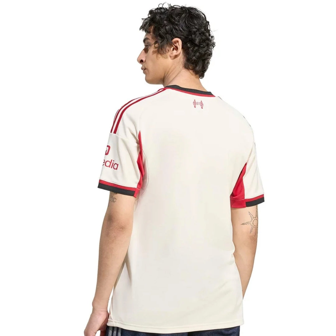 Hombre mostrando la parte trasera de la camiseta Liverpool away 2025-2026 blanca con detalles rojos, Reino del Futbol.