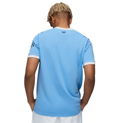Hombre de espaldas con camiseta azul Manchester City, Reino del Futbol, fondo blanco
