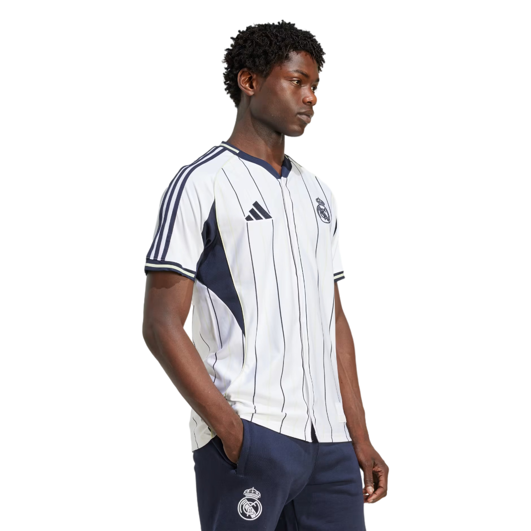 Hombre vistiendo camiseta de fútbol Real Madrid blanca con rayas, ropa deportiva europea.