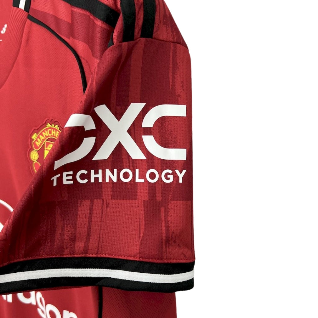 Detalle de la nueva camiseta local Manchester United 2025/26, logo DXC y escudo visible.
