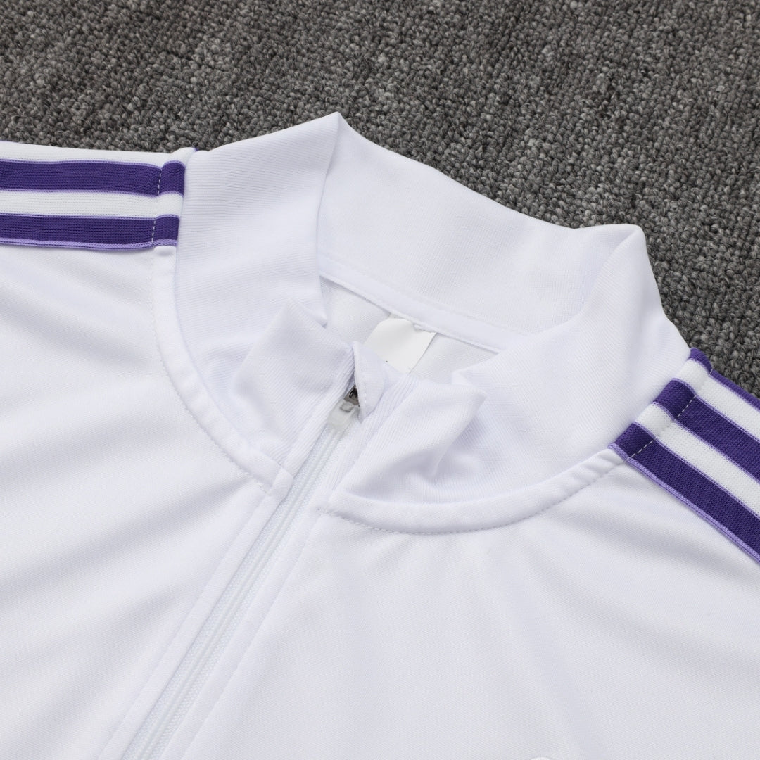 Detalle de chaqueta deportiva blanca con cremallera y líneas moradas, Reino del Futbol
