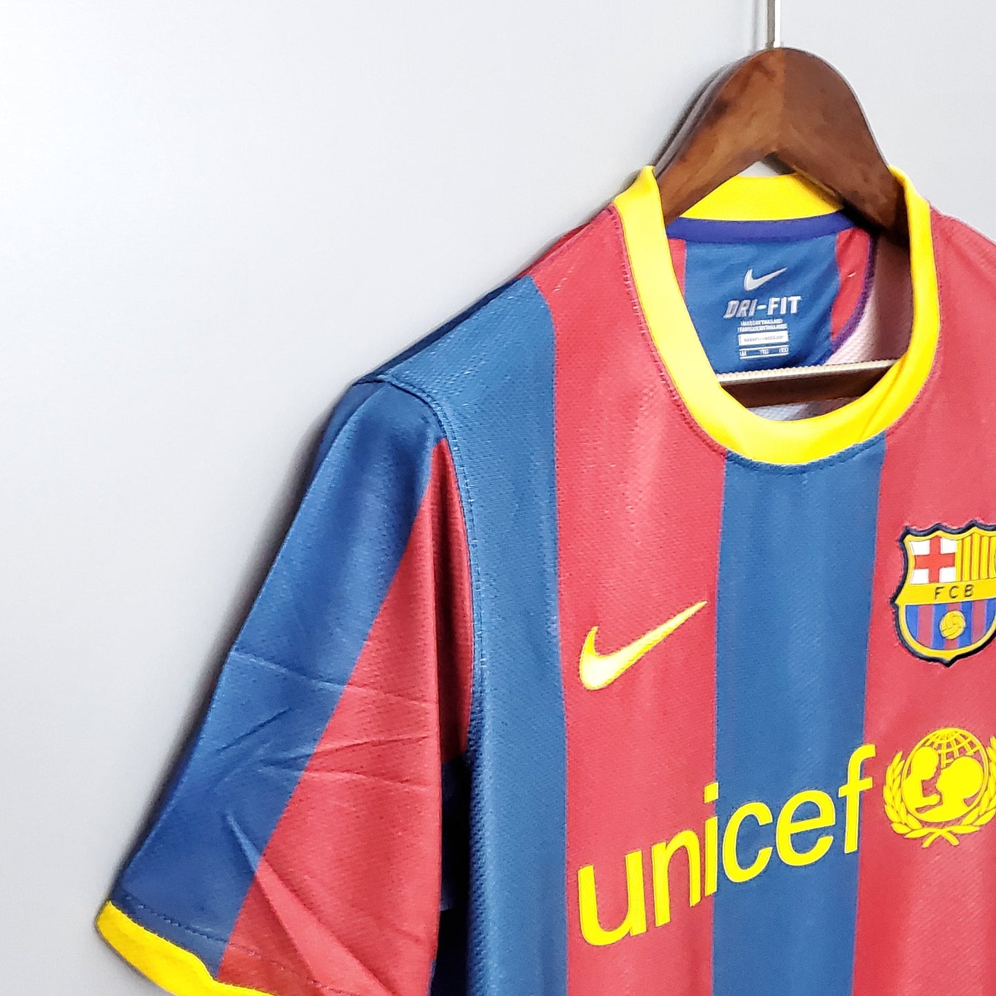 Camiseta de fútbol azulgrana del FC Barcelona, escudo FCB y logo Nike, colgada en percha