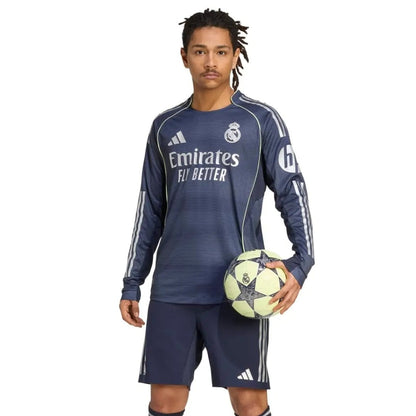 Jugador con uniforme azul Real Madrid 2025 2026 manga larga sosteniendo balón de fútbol, Reino del Futbol