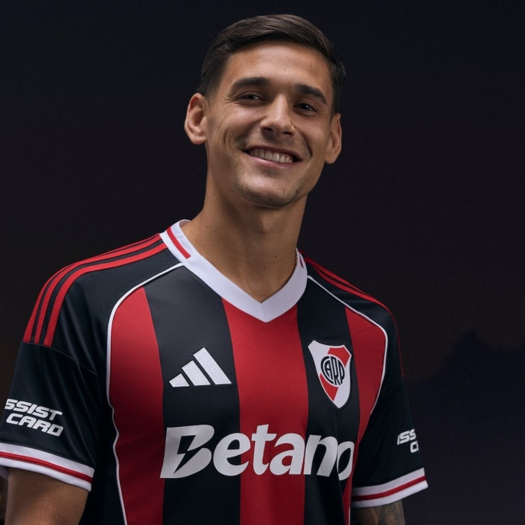 Camiseta River Plate 2026 visitante negra y roja, modelo sonriente, fondo oscuro