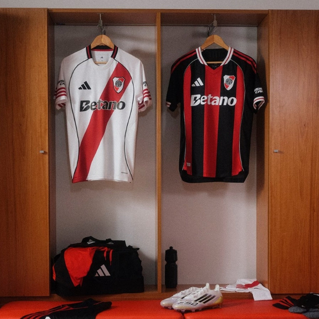 Dos camisetas de fútbol River Plate 2026 en vestuario, una blanca y una negra, venta online en Reino del Futbol.
