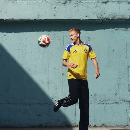 Aficionado con camiseta de Suecia 2026 jugando fútbol frente a pared azul, Reino del Futbol