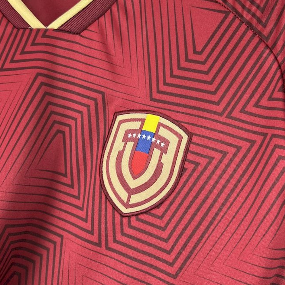 Detalle de la camiseta vinotinto de Venezuela con escudo y patrón geométrico, fútbol 2026.