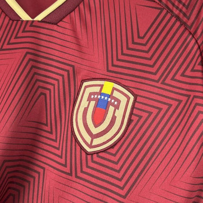 Detalle de la camiseta vinotinto de Venezuela con escudo y patrón geométrico, fútbol 2026.