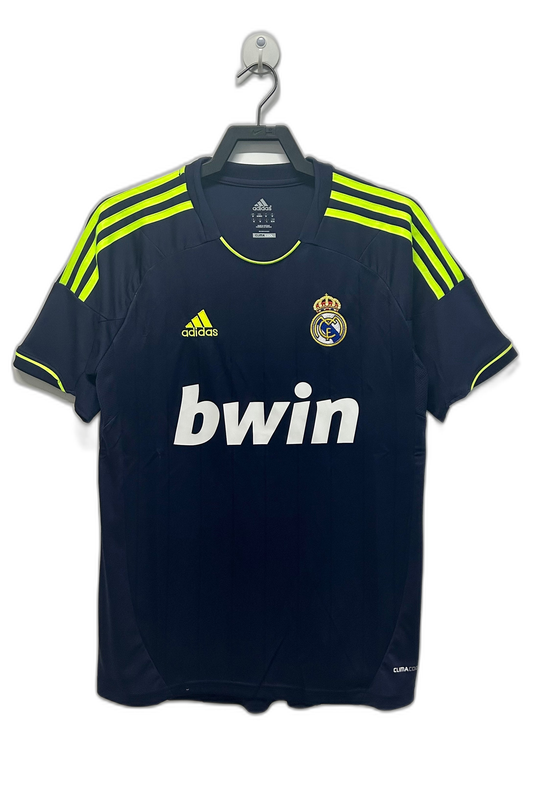 Camiseta Real Madrid 2012-13 visitante retro azul marino, detalles amarillo flúor, logo Adidas y escudo.