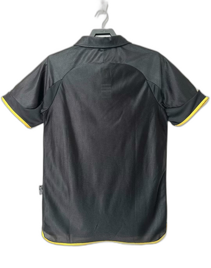 Camiseta retro Real Madrid 1999-2001 negra con detalles amarillos, vista trasera, Reino del Futbol