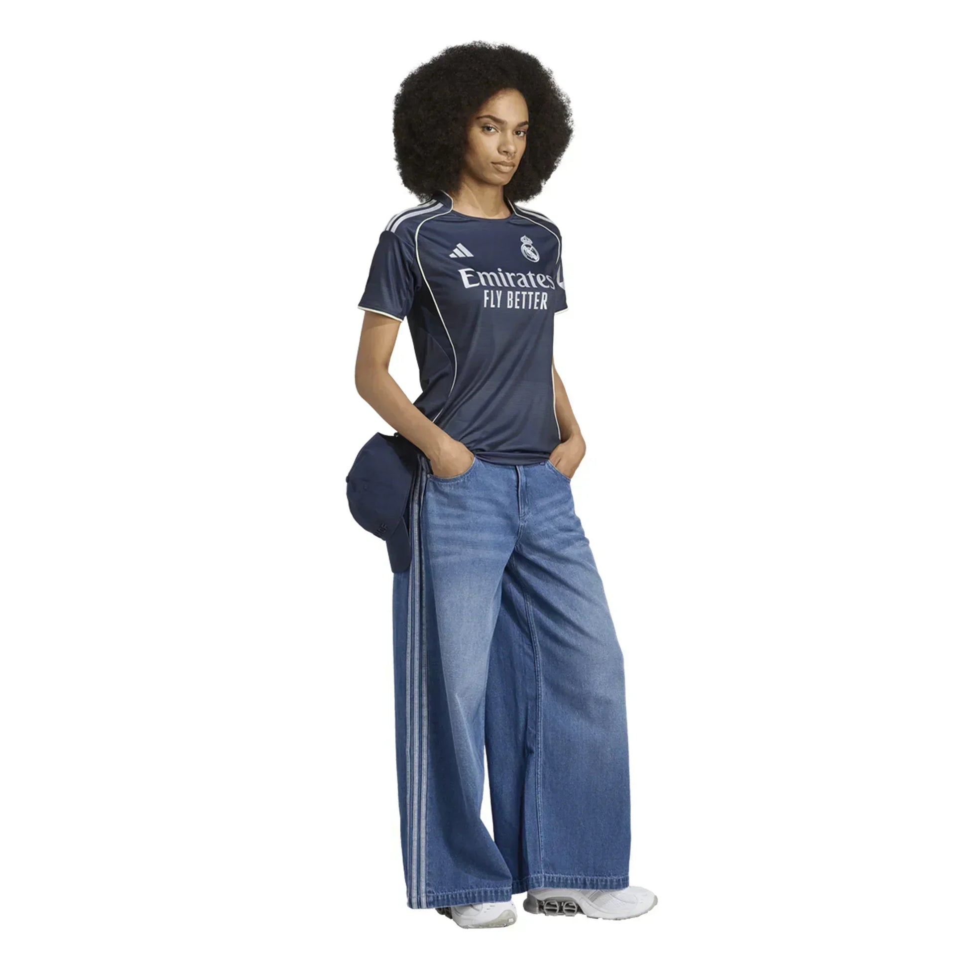 Mujer con camiseta de fútbol Real Madrid azul y vaqueros anchos, estilo deportivo casual